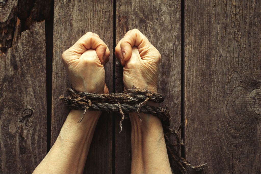 A photograph of a modern slavery victim with their hands tied together with rope.
